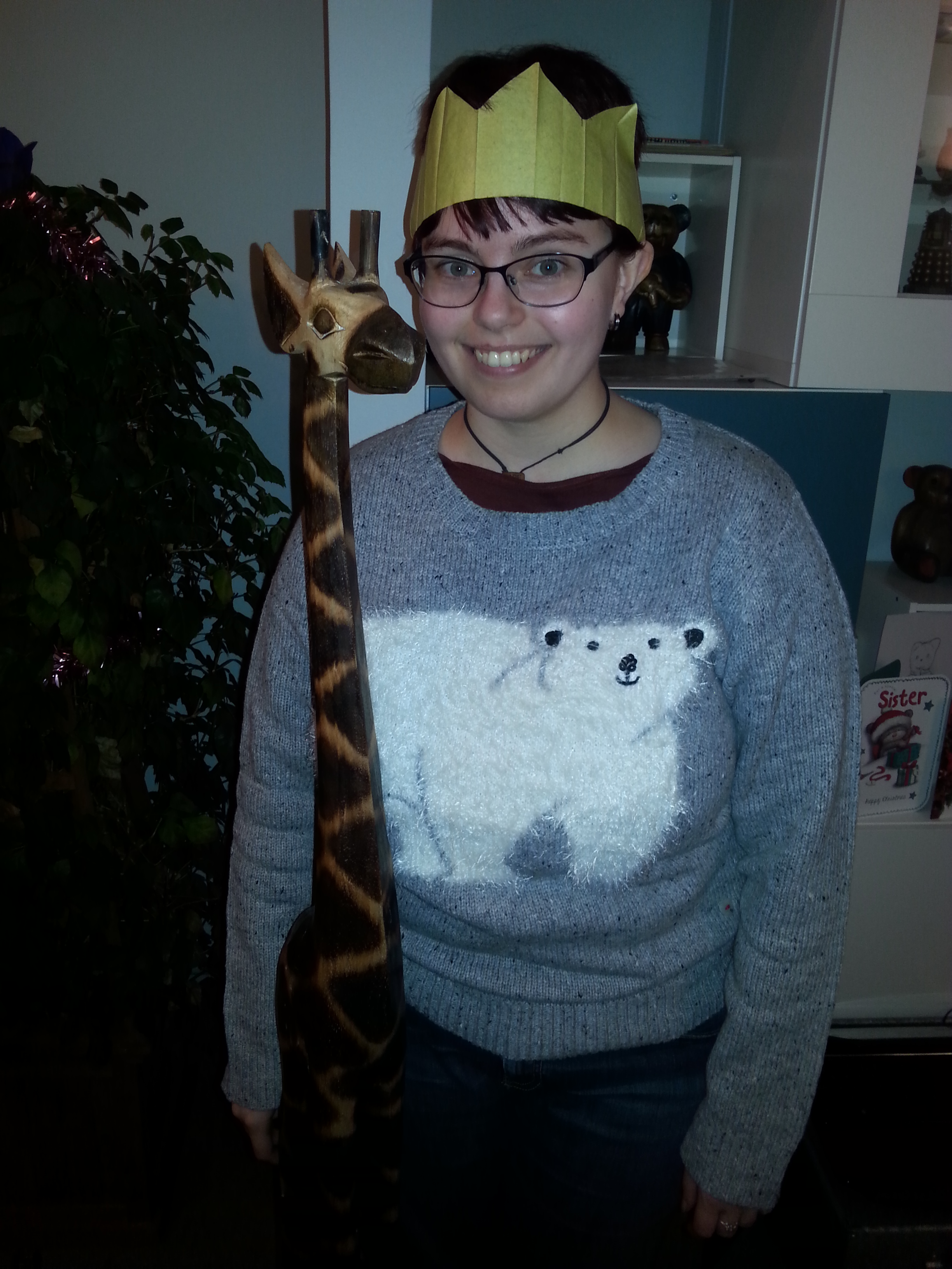Photo of me wearing a paper party hat, next to my five foot tall giraffe