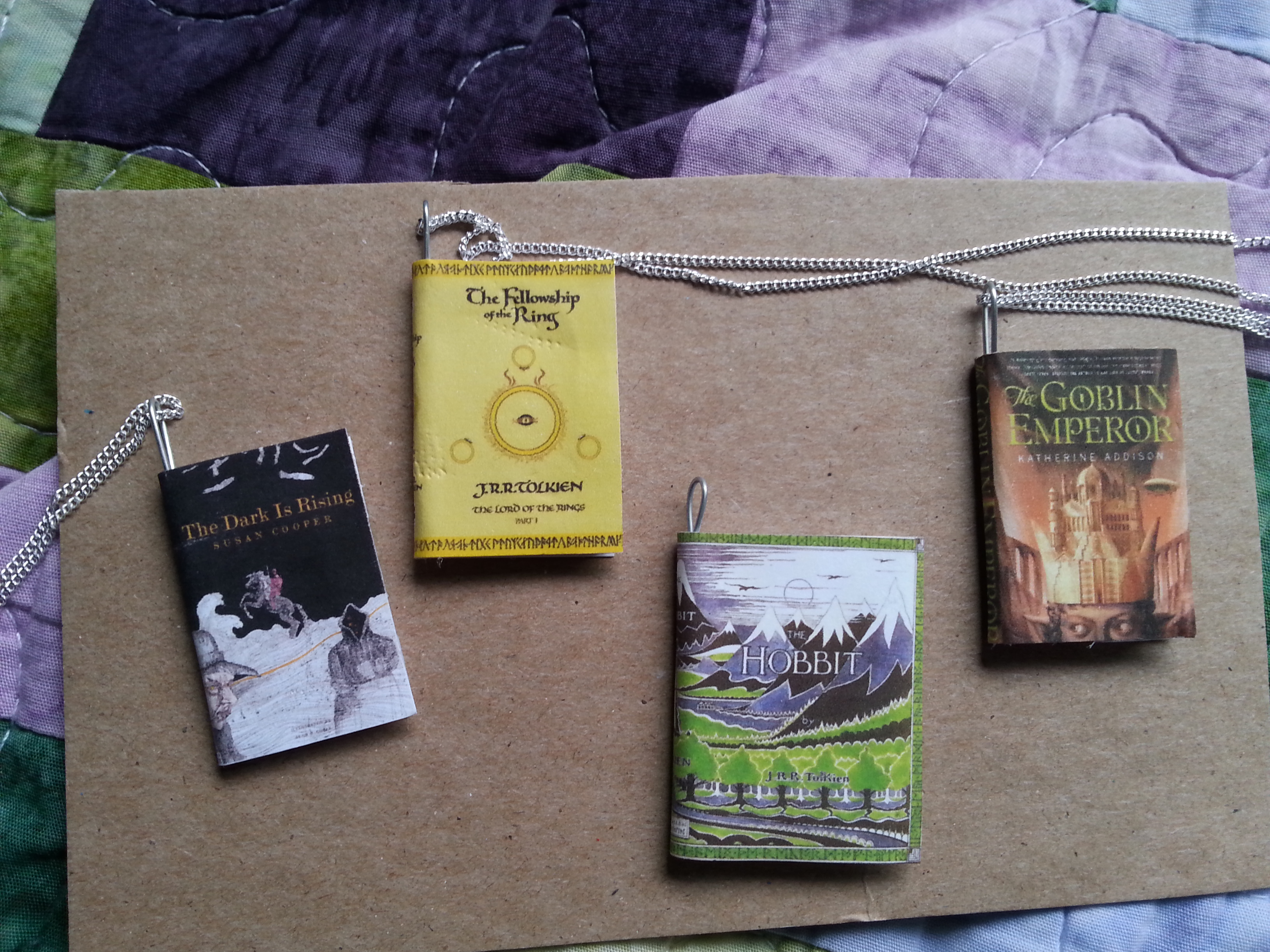 Four book necklaces: Lord of the Rings, The Hobbit, The Dark is Rising and The Goblin Emperor