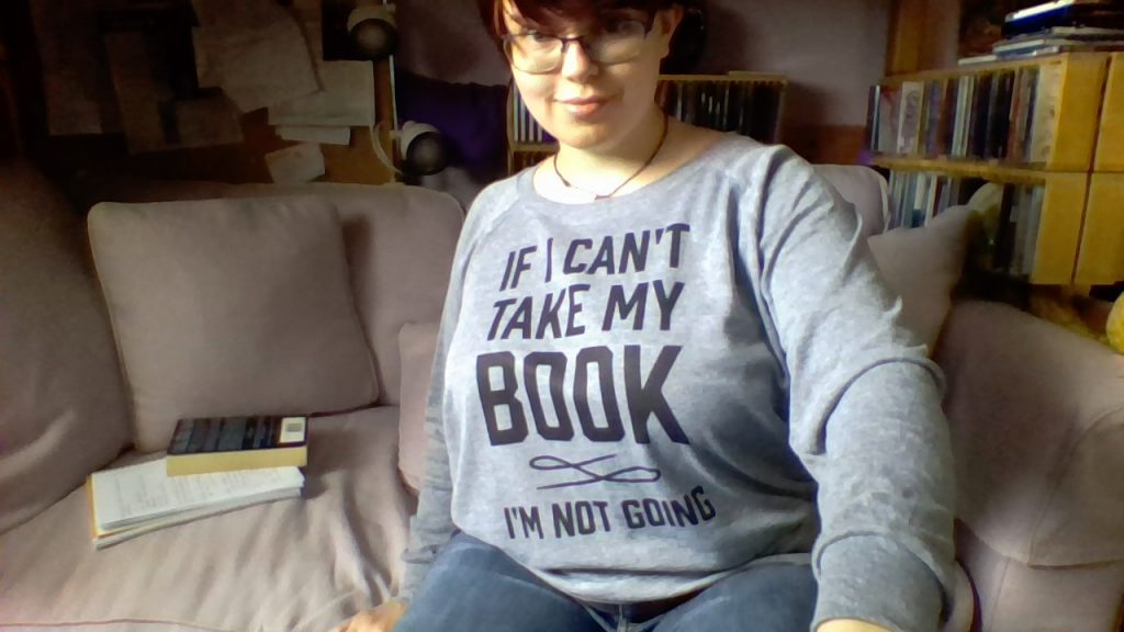 Photo of me, wearing a grey sweatshirt with the text "If I can't take my book, I'm not going"
