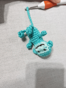 A stitched monkey plays on a branch that looks rather like a crochet hook